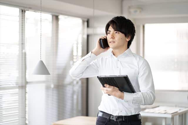 電話を耳に当てるカジュアルな服装のビジネスマン