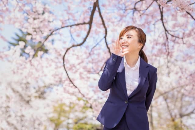 桜の木とスーツ姿の女性