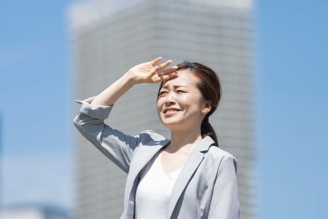 真夏の日差しを浴びるスーツ姿の女性