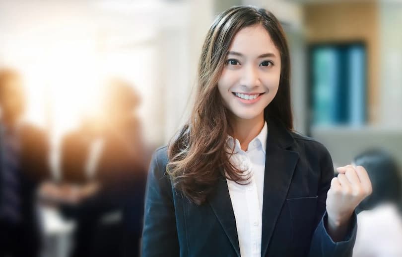 ガッツポーズをするスーツ姿の若い女性