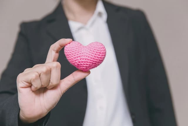 ハートを掲げるスーツ男性
