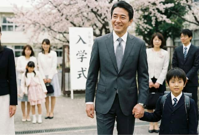 入学式で子どもと手を繋ぐ落ち着いた父親